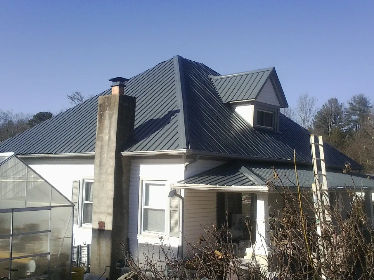 Dark blue standing seam metal roof on a white farmhouse with dormer — Slate & Tile Roof Repair by Roofing Brothers in Little Compton