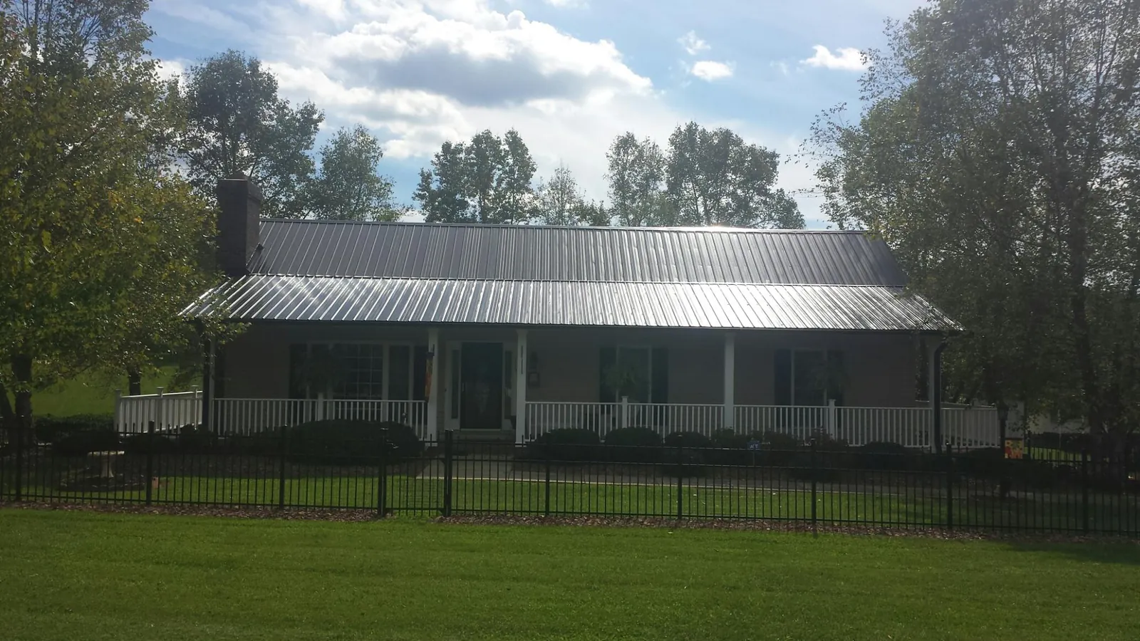 Gray metal roof on a brick ranch with a full width front porch — Gutter Guard Installation work by our crew in Little Compton